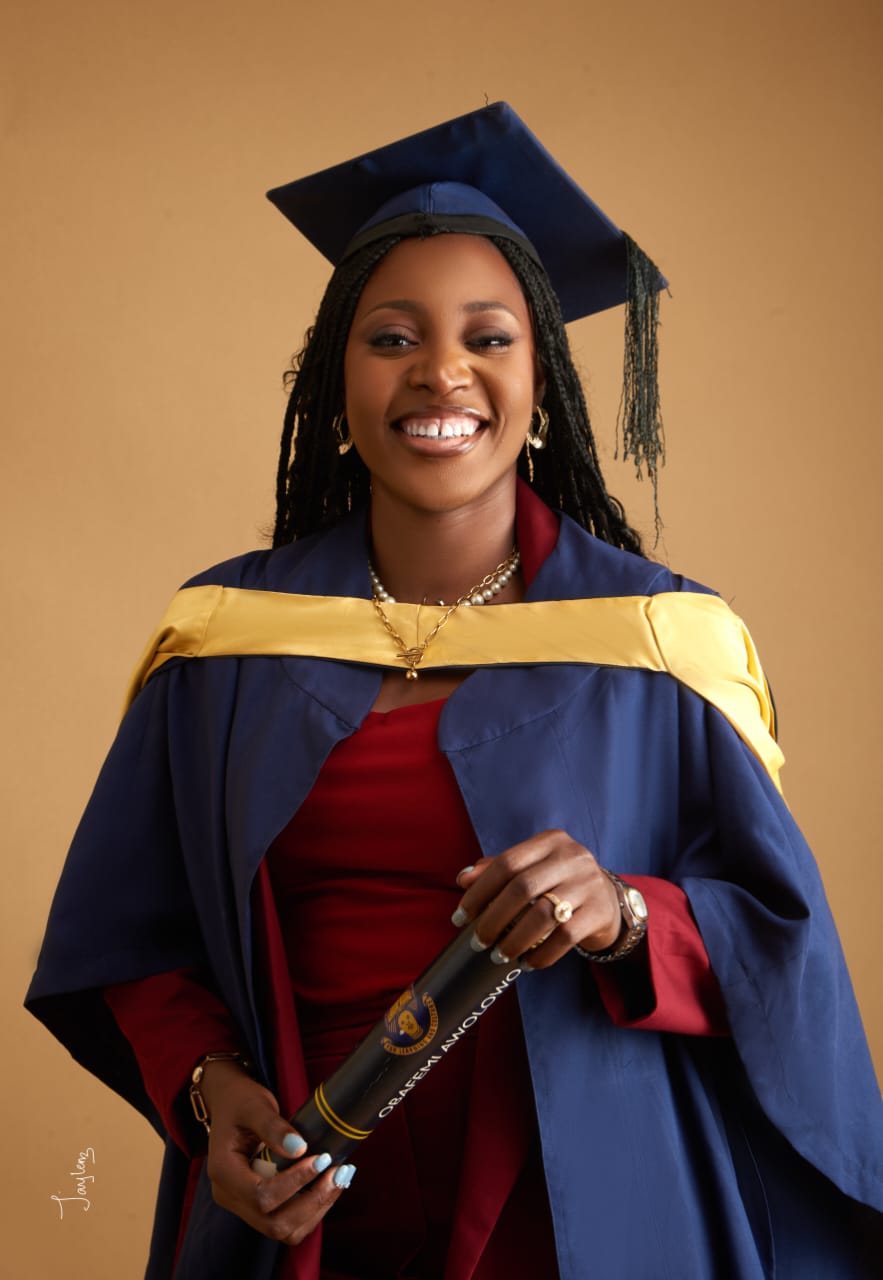 Priscilla smiling in her graduation gown and holding her certificate