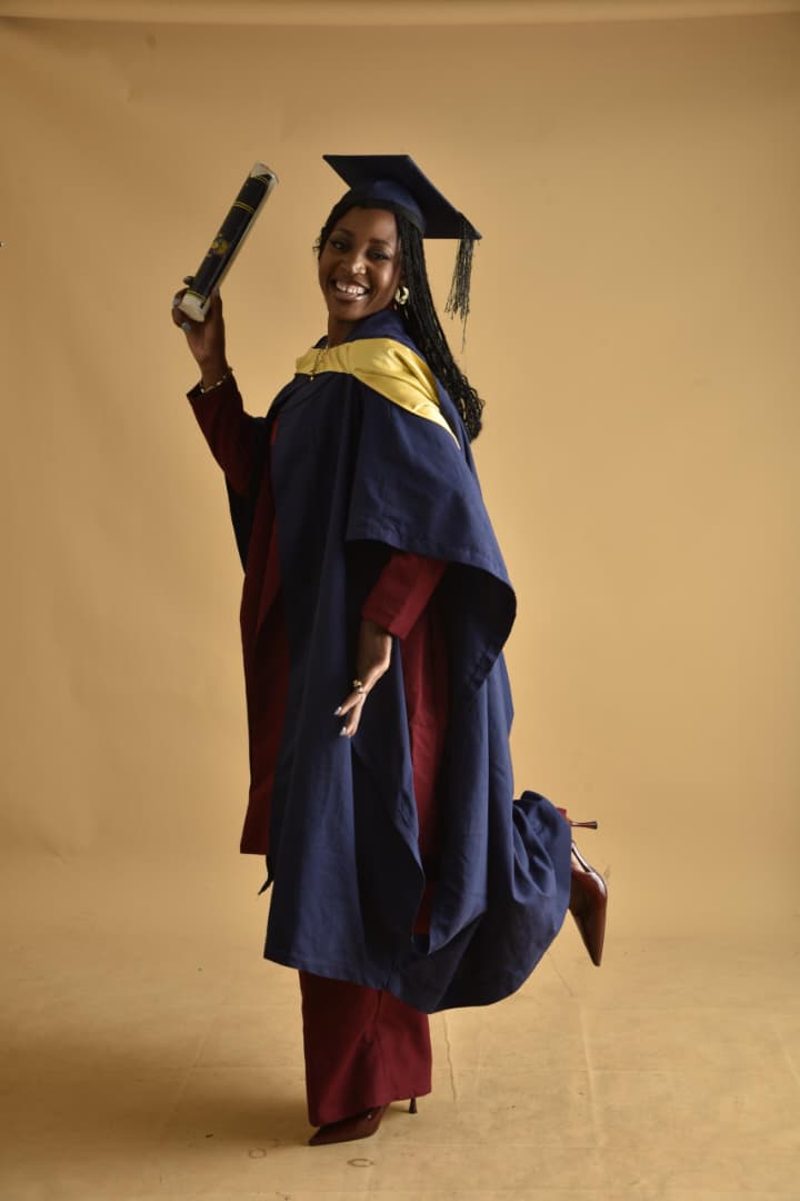 Priscilla posing joyfully in her graduation gown